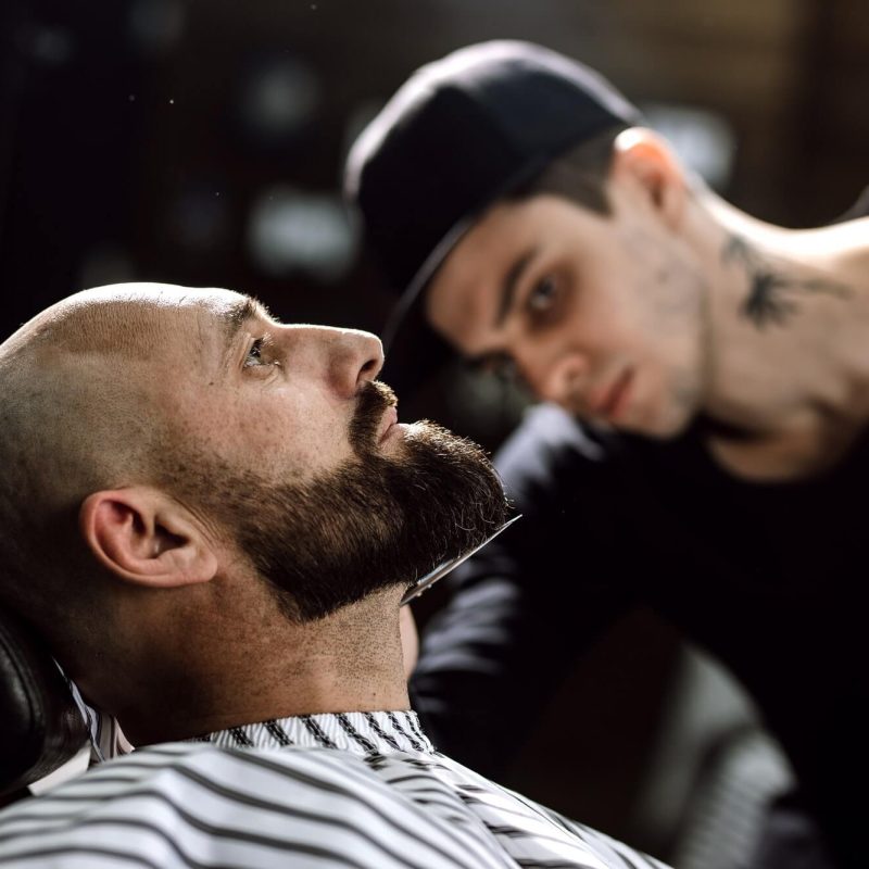 the-barber-dressed-in-a-black-clothes-scissors-beard-of-brutal-man-in-the-stylish-barbershop.jpg